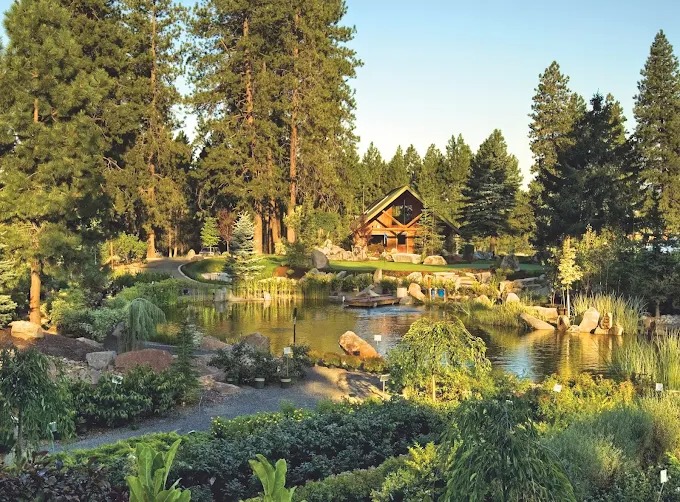 Large pond water feature with boulder outcrops and pines at sunset