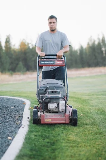Crew member mowing a lawn with a walk-behind mower