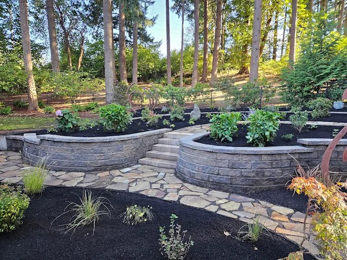 Terraced block retaining walls with mulched planting beds and flagstone